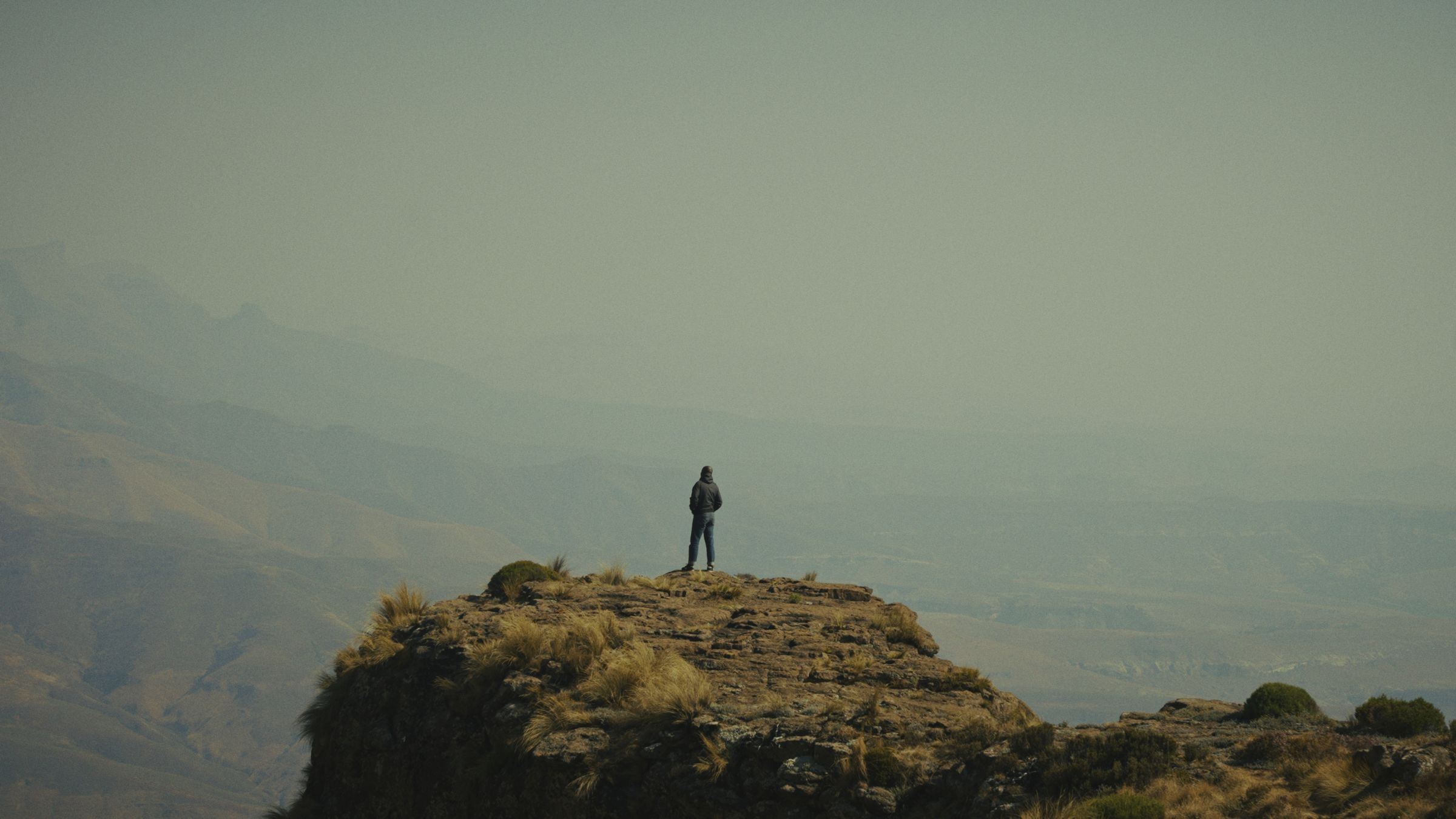 Jabulile Majola standing on a rocky outcrop above a hazy mountain valley